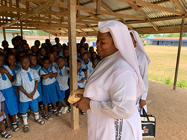 A Sister of Caring Aid with schoolchildren in Nigeria